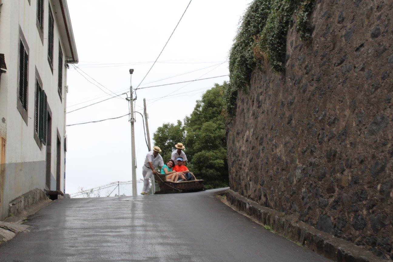 Turistas a sorrir durante a descida de carro de cesto na Madeira