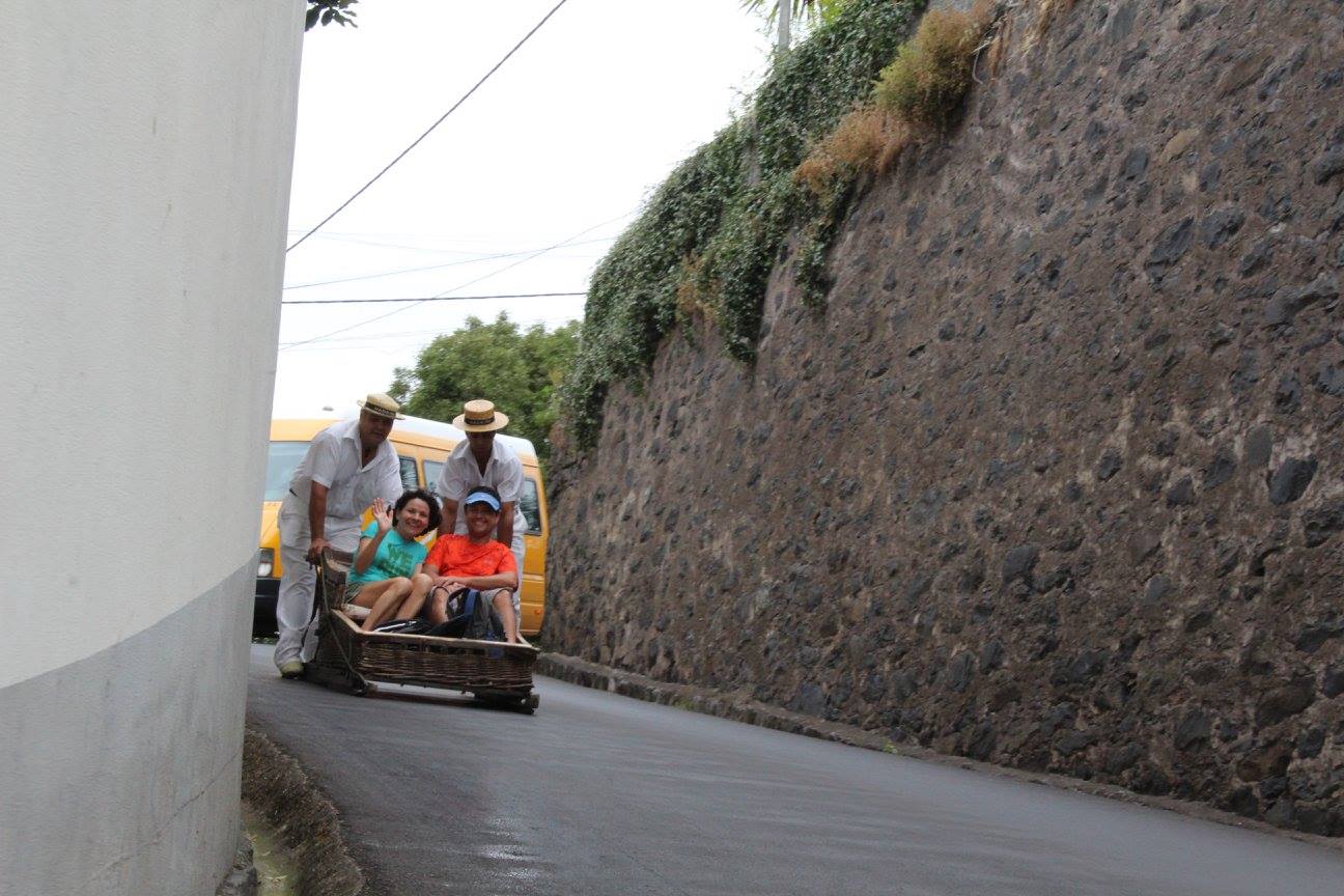 Carro de cesto de vime com turistas durante a descida do Monte