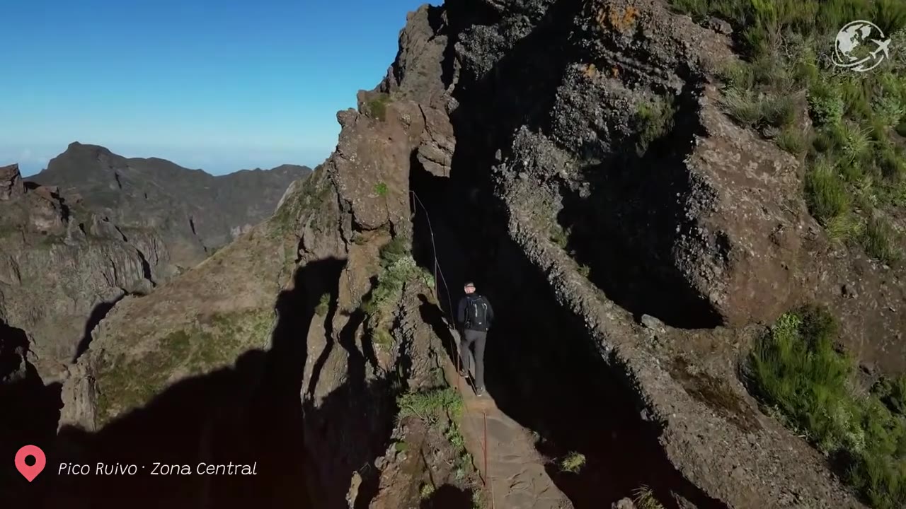 Caminhantes percorrendo a trilha de pedra em direção ao cume do Pico Ruivo, acima de um mar de nuvens na Madeira