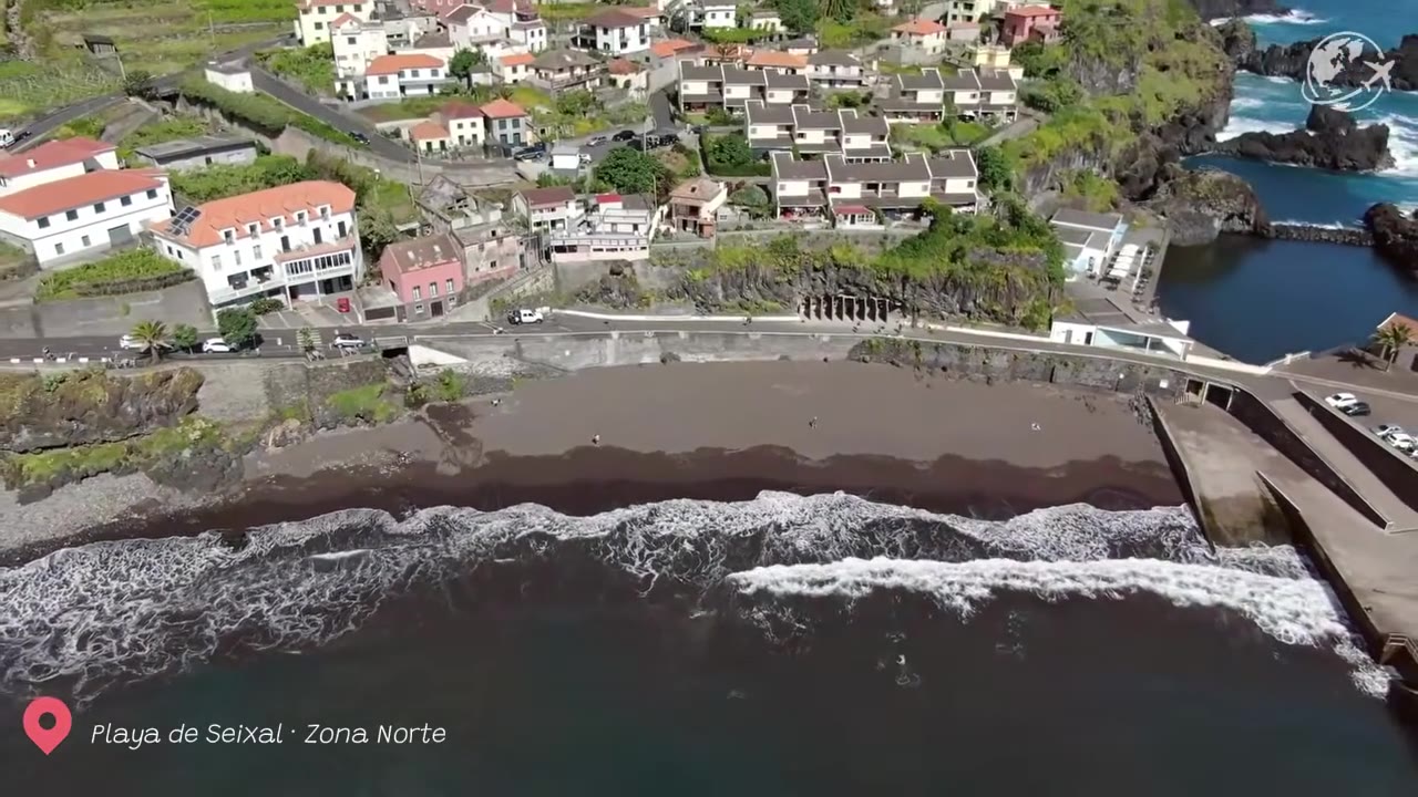 Praia de areia vulcânica preta no Seixal, com falésias verdes e as ondas do Atlântico, na costa norte da Madeira